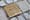 Ein Stolperstein zwischen grauen Steinen eines Bürgersteigs